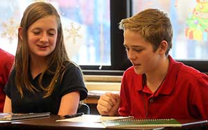 Eighth-graders Rae Davel, left, and Jordan Roberts converse during English class at St. John Vianney School in Brookfield on Monday, Jan. 21. Roberts recently moved from Kansas, and began his first day at St. John Vianney School on Friday. (Catholic Herald photo by Allen Fredrickson)