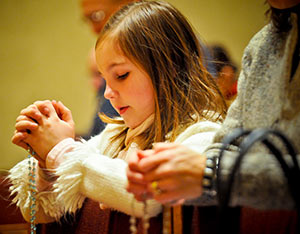 Anna Maria Krupka and her mother, Mary Miceli-Krupka, only partially visible, pray the rosary at Saint Francis Seminary, St. Francis, during the 10th anniversary celebration of the Rosary Evangelization Apostolate on Tuesday, Feb. 19. (Catholic Herald photo by Juan C. Medina)