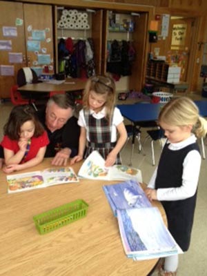 Salvatorian Fr. Robert Marsicek reads International Baccalaureate books with Wauwatosa Catholic students, Morgan Vosniak, left to right, Ruby Scheuing and Erin Hemsworth on Friday, Jan. 25. (Submitted photo by Heidi Hernandez)
