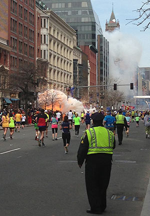 Runners head to finish line of the Boston Marathon as an explosion erupts nearby April 15. Two bombs exploded in the crowded streets near the finish line of the marathon, killing at least three people, including an 8-year-old boy, and injuring more than 140. (CNS photo/Dan Lampariello, exclusive to Reuters)