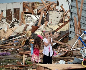 Two girls stand in rubble after a tornado struck Moore, Okla., May 20. The mile-wide tornado touched down near Oklahoma City, killing dozens, including many children, destroying homes, businesses and a pair of elementary schools in the suburb of Moore. (CNS photo/Gene Blevins, Reuters)