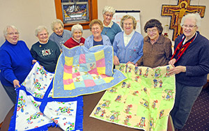 Members of the Quilting Society show off some of their handiwork during one of their meetings in February. Pictured left to right are Connie Kirsch, Margaret Hemb, Dorothy Wallander, Lolly Fox, Jean Forsterling, Virgina Radke, Jo Bubb, Annette Thimmig and Jeanette Lane. (Catholic Herald photos by Sam Arendt)