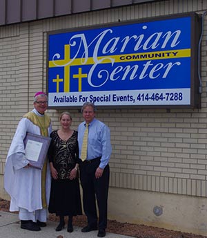 Bishop Donald J. Hying poses with Marian Center International owners Kathy Frassetto-Suhr and Bill Suhr outside the building they recently purchased. The building, called Marian Community Center, blessed by spiritual advisor Bishop Hying on April 7, will be used for author visits, lectures and meetings and will be available for party rentals. (Submitted photo courtesy the Marian Center)