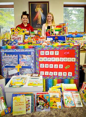 Nicole Conforti, left, and Angealic Kaye, confirmation classmates at St. Mary of the Hill Parish, Hubertus, pose in mid-January, with some of the supplies they collected for two kindergarten classes at Guardian Angel School in Manhattan, a school that was heavily damaged by Hurricane Sandy. (Catholic Herald photo by Juan C. Medina) 