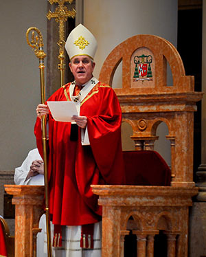 Standing at the cathedra in the Cathedral of St. John the Evangelist on Petecost Sunday, May 19, Archbishop Jerome E. Listecki reads the decree convoking an Archdiocesan Synod to be held Pentecost weekend, June 7-8, 2014. The archbishop read the decree during the 8 a.m. (Catholic Herald photo by Juan C. Medina)