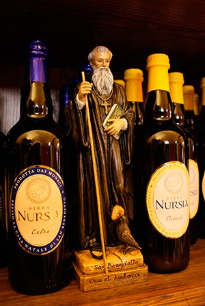 A statue of St. Benedict is seen between a bottle of "Extra" dark beer and the "Bionda" blond beer at the brewery of St. Benedict's Monastery in Norcia, Italy, Aug. 14. (CNS photo/Henry Daggett)