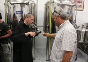  Benedictine Fr. Cassian Folsom, prior of St. Benedict's Monastery, pours beer for a guest at a tasting commemorating the first anniversary of the monastery's brewery in Norcia, Italy, Aug. 14 (CNS photo/Henry Daggett)