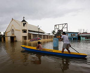 People make their way by boat past a church along a flooded road in Bulacan, Philippines, Aug. 21. Hundreds of thousands of people in metro Manila and surrounding areas have been affected by heavy monsoon rains and flooding. (CNS photo/Erik de Castro, Reuters)