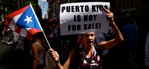 Woman protests near the office of a hedge fund manager in New York Aug. 13 over the financial crisis gripping Puerto Rico. A Senate committee held hearings Oct. 22 to discuss solutions to the crisis. (CNS photo/Justin Lane, EPA)