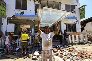 Residents recover some of their belongings April 25 from debris of a destroyed building in Canoa, Ecuador. Catholic agencies will begin building temporary shelters for thousands of families displaced by the April 16 magnitude-7.8 earthquake, the country's worst natural disaster in nearly seven decades. (CNS photo/Jose Jacome, EPA, Reuters)