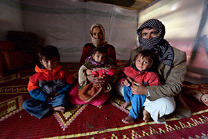 A refugee family from Syria poses for a photo in 2012 in their tent in Lebanon. Pope Francis' postsynodal apostolic exhortation on the family, "Amoris Laetitia" ("The Joy of Love"), was to be released April 8. The exhortation is the concluding document of the 2014 and 2015 synods of bishops on the family. (CNS photo/Paul Jeffrey)