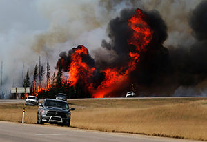 Smoke and flames from the wildfires erupt behind cars on the highway near Fort McMurray, Alberta. Pope Francis has added his name to the list of people offering condolences to those affected by the massive forest fire that has led to the evacuation of Fort McMurray. (CNS photo/Mark Blinch, Reuters)