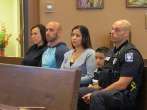 Anne Spaulding, left to right, Officer Joe Spaulding, Tina Ortiz, Rob Ortiz Jr., and Officer Rob Ortiz, listen to Xaverian Fr. Alejandro Rodriguez’s homily during the Friday, May 20 Blue Mass celebrated for public safety officials at  St. Richard Parish, Racine. (Submitted photo courtesy Eloy Contreras)