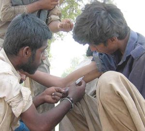 A Pakistani man injects a heroin-filled syringe into a man in 2011 on the streets in Multan. Pope Francis has requested a special study session at the Vatican to look at how to solve the growing problem of drug abuse, especially narcotics. (CNS photo/MK Chaudhary, EPA)