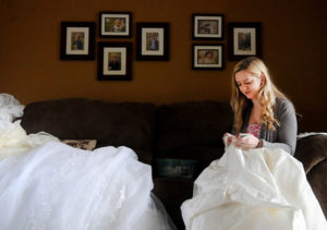 Sarah Novak does the delicate work of taking apart donated wedding dresses April 27 at her home in Rice, Minn., so the material can be reused to make garments to give families grieving the loss of a child. (CNS photo/Dianne Towalski, The Visitor)