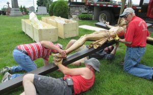 As part of the 175th anniversary celebration at St. John the Baptist, Johnsburg, Saturday, June 18, Archbishop Jerome E. Listecki will bless the new crucifixion statuary in the parish cemetery. Left, Dave Nickel (striped shirt) and Mike Schroedl secure the feet of the corpus to the cross, June 2, while Chuck Schroedl and Bernie Schroedl hold the cross. (Submitted photo courtesy St. John the Baptist Parish, Johnsburg)
