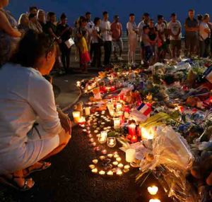 People gather around flowers and burning candles July 17 to pay tribute to victims of the Bastille Day attack in Nice, France. Pope Francis prayed that God may give comfort to grieving families and foil the plans of those who wish to harm others. (CNS photo/Pascal Rossignol, Reuters)