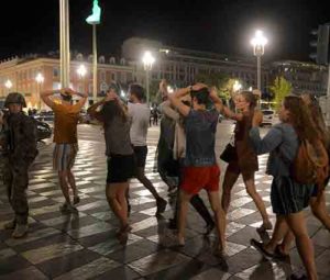 People cross the street with their hands on their heads as a French soldier secures the area July 15 after at least 84 people were killed along the Promenade des Anglais in Nice, France, when a truck ran into a crowd celebrating the Bastille Day national holiday July 14. (CNS photo/Jean-Pierre Amet, Reuters)