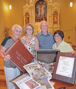 Members of Immaculate Conception Parish, Saukville, prepare a time capsule of items from the parish’s history prior to its last Mass before merging into St. John XXIII Parish. Pictured are Barbara Pierron, left to right, Connie Coen, Urban and Judy Braam. (Catholic Herald photo by Sam Arendt)