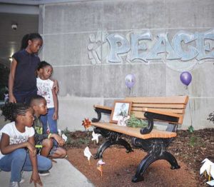 Sibilings Victoria, dark blue shirt, Michelle, Daniel and Melissa Okoro, stop at the peace garden at Northwest Catholic School, Milwaukee, following a dedication ceremony, Sept. 16. The garden was created to honor the memory of Laylah Petersen who was killed in her home by an errant bullet nearly two years ago. A photo of Laylah is resting on the bench. (Catholic Herald photo by Juan C. Medina)