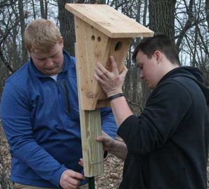 Patrick Donohue, left, and Jonathon Wallace, students at Marquette University High School, Milwaukee, install a wooden nest box for bluebirds on the grounds of the Schoenstatt Retreat Center, Waukesha, in late spring. (Submitted photo courtesy Joe Meyer) 
