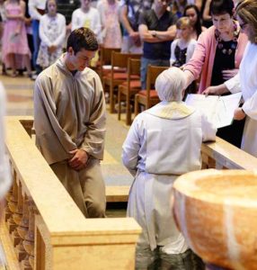 Andrew Landerholm listens as Fr. Jeff Haines, rector and pastor of the Cathedral of St. John the Evangelist, Milwaukee, reads the Rite of Baptism during the Aug. 6 Mass at which the MSOE student received the sacraments of initiation. (Catholic Herald photos by Peter Fenelon) 