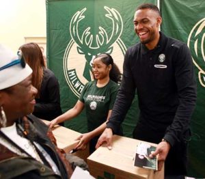 Jabari Parker hands a box containing fixings for an entire Thanksgiving meal to a client of Capuchin Community Services. The Milwaukee Bucks player paid for the cost of the food and distributed it with the help of students from Messmer and Divine Savior Holy Angels high schools.
