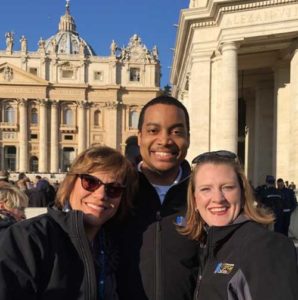 Members of the Milwaukee Mercy Choir, Peg Kasun, (left to right) Aaron Mathews and Maria Notch, pose for a photo with the Vatican in the background during their Nov. 14-22 trip to Italy. (Submitted photo courtesy the Milwaukee Mercy Choir)